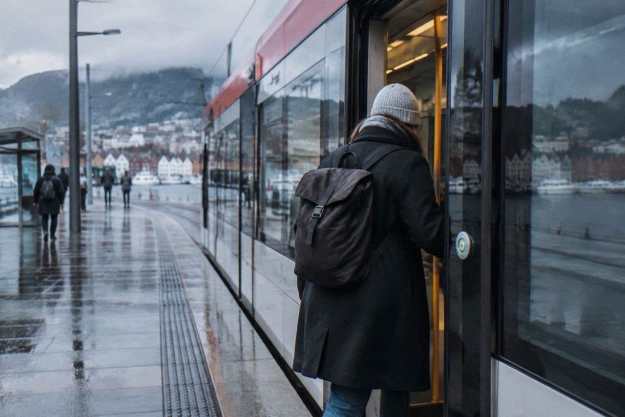 A passenger boarding a light rail tram at a street stop in central Bergen