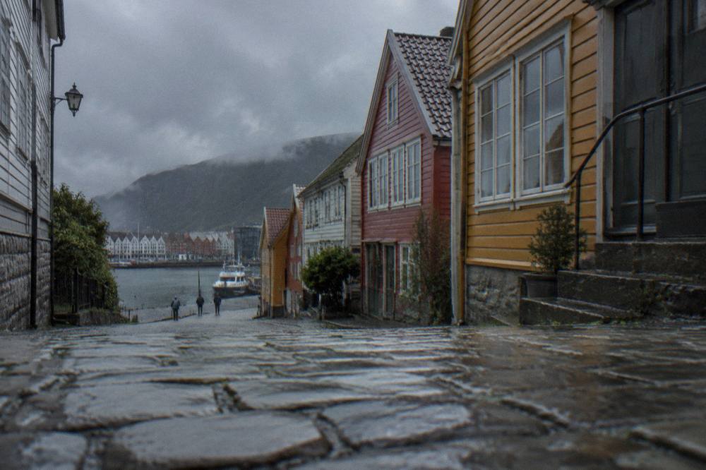 A rain-wet cobblestone street lined with colourful wooden houses in central Bergen