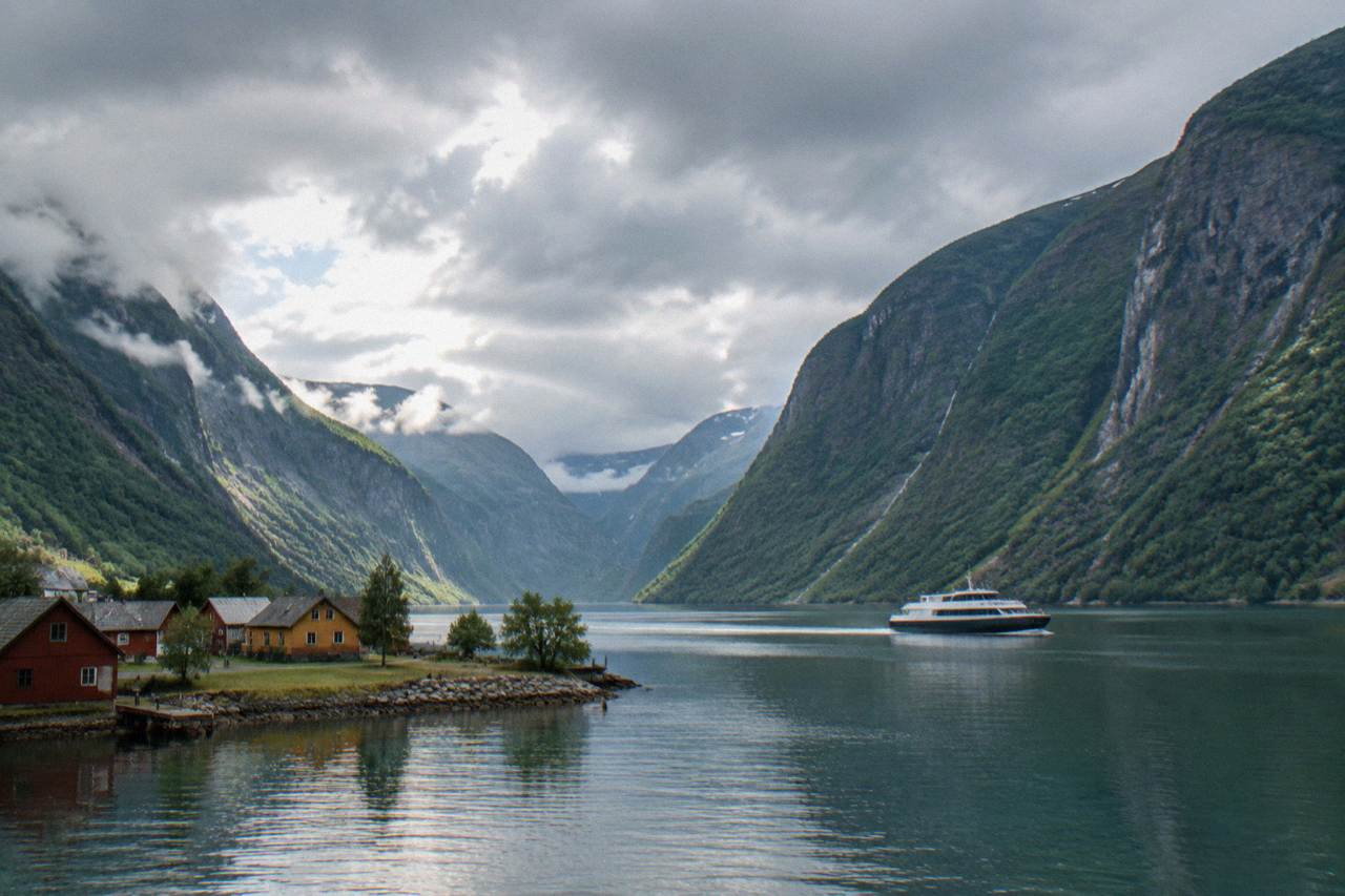A passenger boat crossing calm water between steep green fjord walls in western Norway