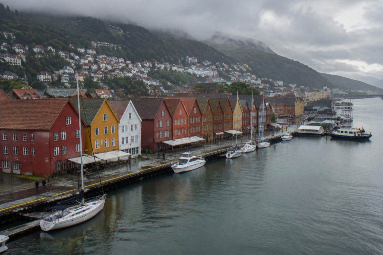 Colourful wooden houses along the Hanseatic wharf in Bergen, with the harbour and hillsides behind them