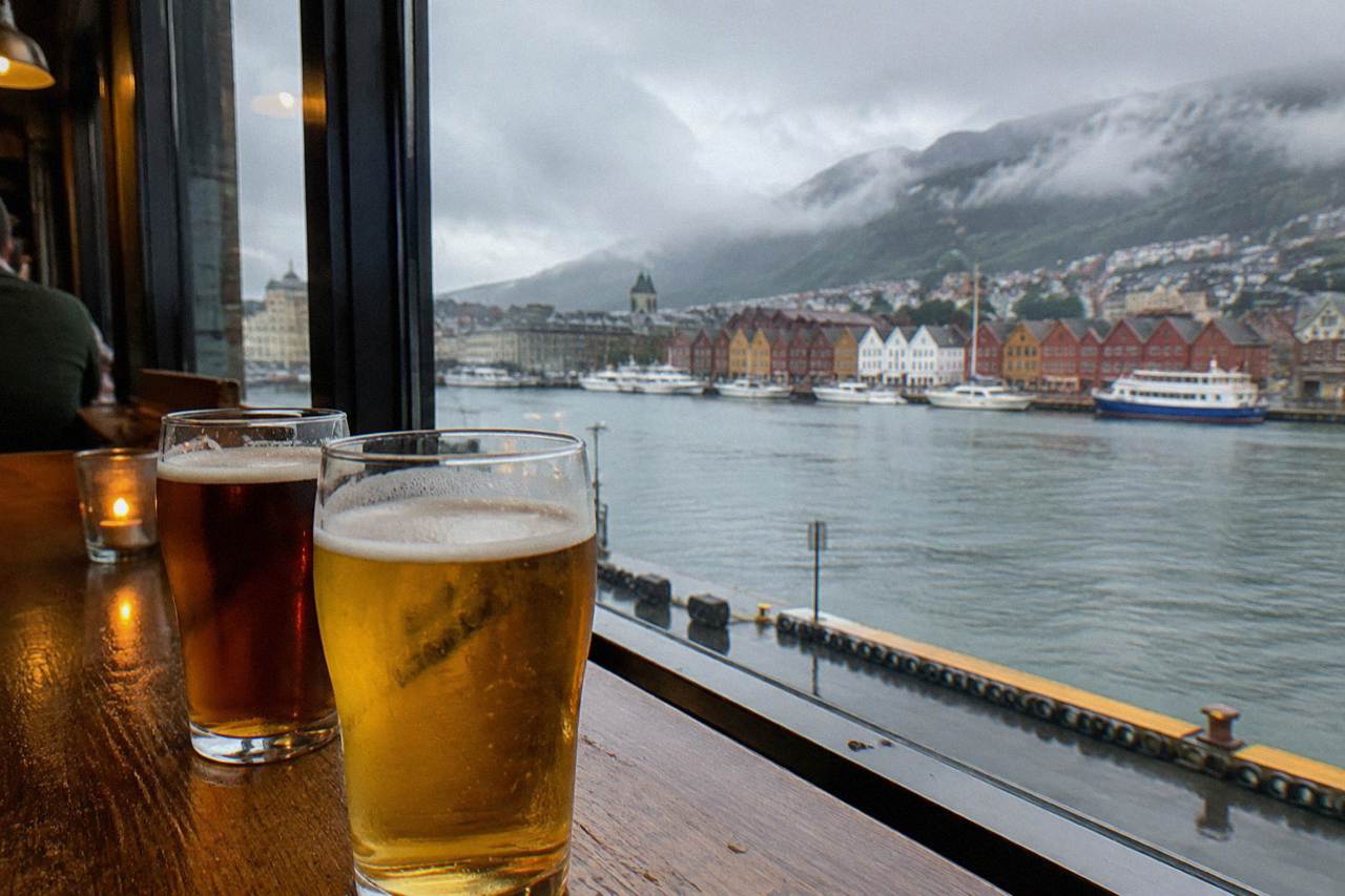 Glasses of beer on a wooden counter in a cozy Bergen bar with warm evening light