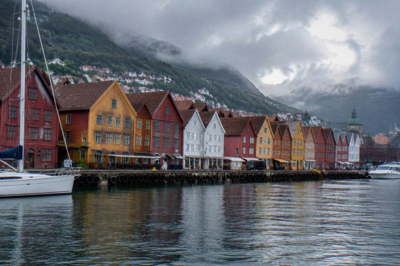 Colourful wooden Hanseatic buildings along the wharf in Bergen seen from across the harbour on a soft grey day