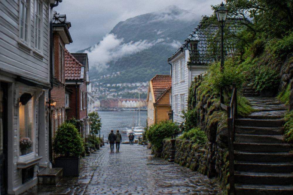 Stone steps and wooden fences climbing the green hillside toward a mountain above Bergen