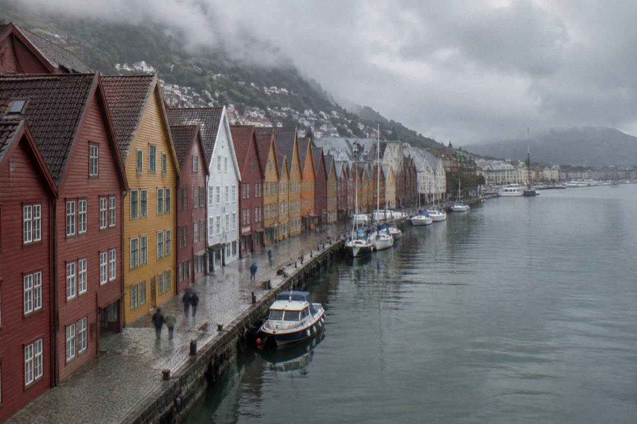 Colourful Hanseatic wooden buildings along the Bryggen wharf in Bergen with small boats on the harbour water