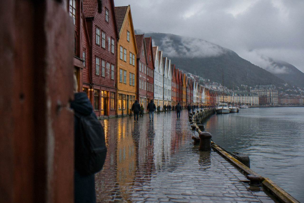 Colourful wooden Hanseatic trading houses along the Bryggen wharf in Bergen reflected in wet cobblestones