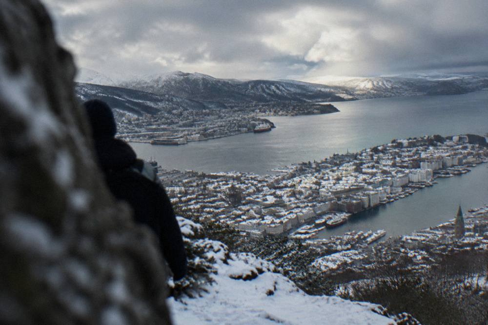 Snow-covered rooftops of central Bergen seen from a mountain above the city