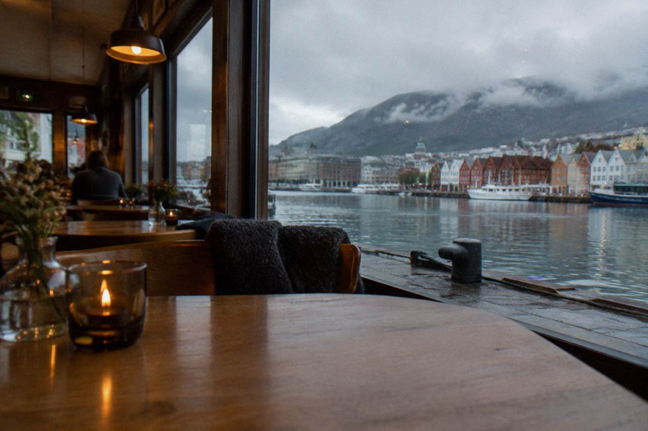 A cosy Bergen restaurant interior with wooden tables and warm evening light