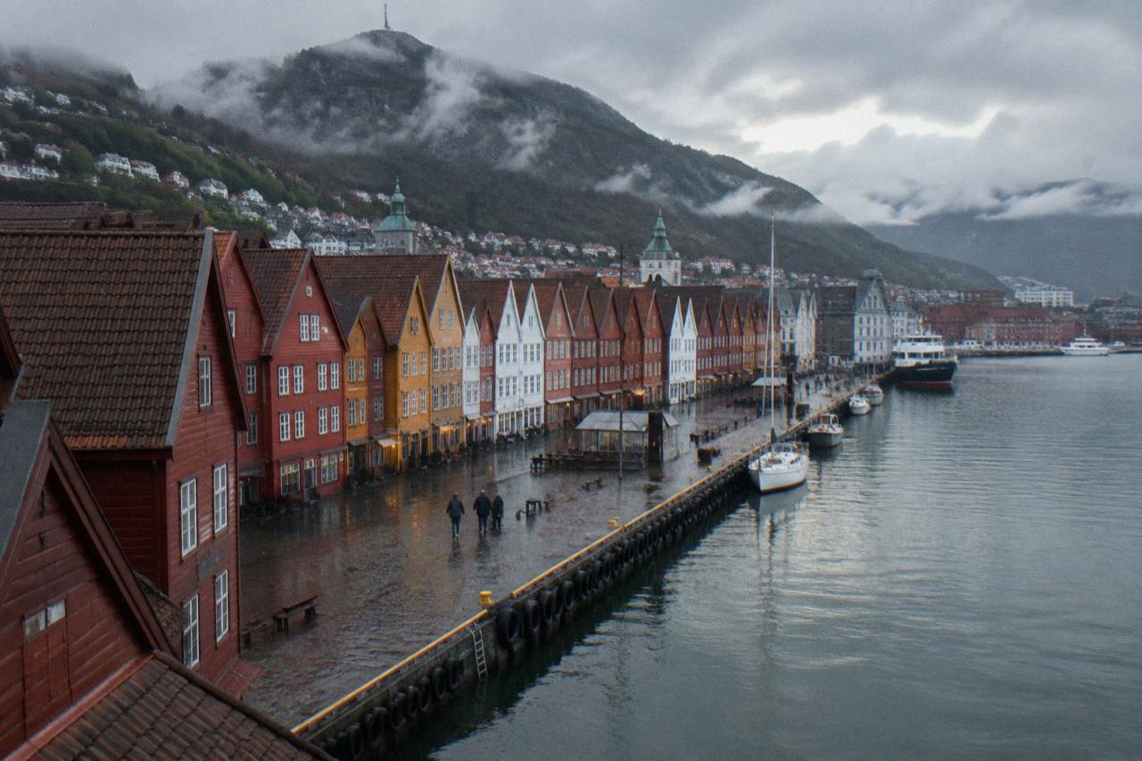 Colorful wooden trading houses along the old wharf in Bergen with steep mountains rising behind the city