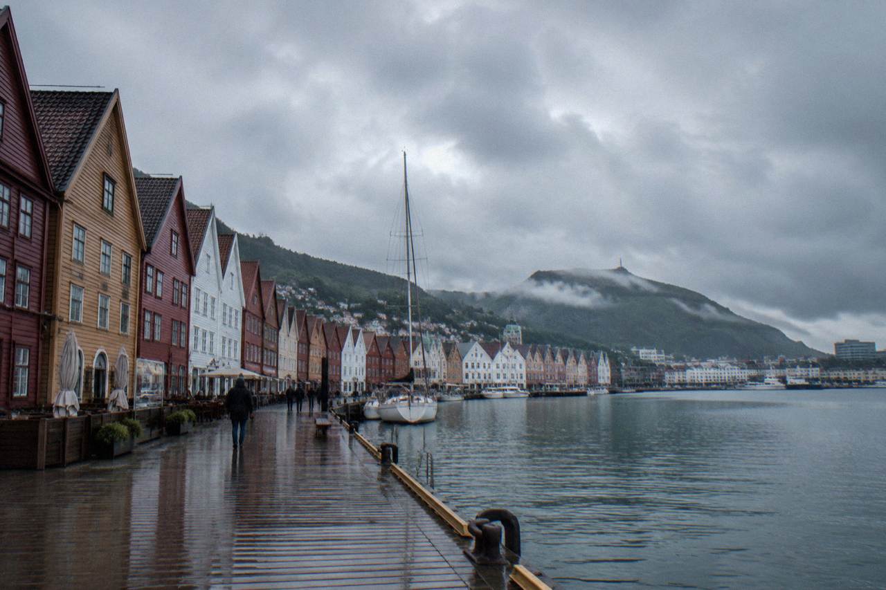Rain-slicked wooden buildings along the Hanseatic wharf in Bergen, Norway, under a dark overcast sky