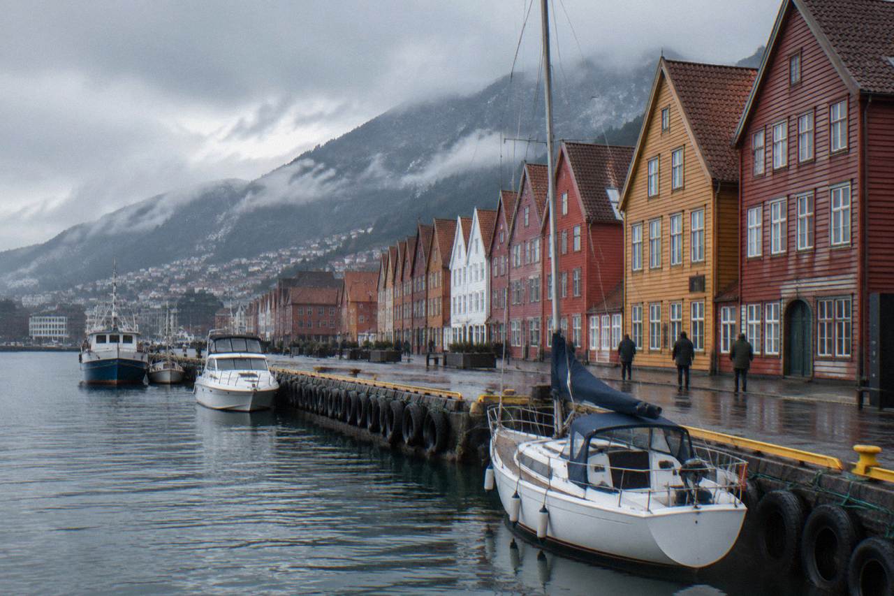 Colourful wooden houses along the historic wharf in Bergen with mountains rising behind the city