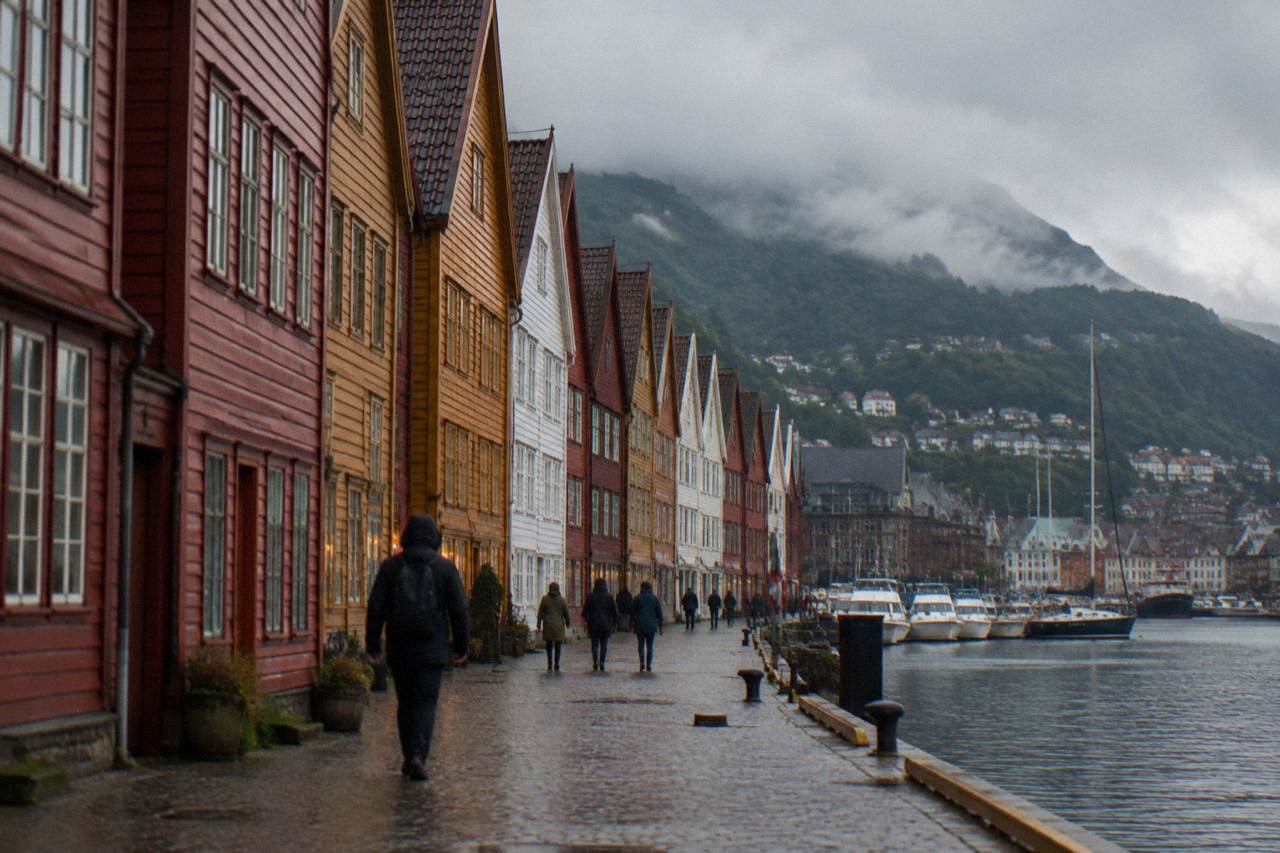 Colourful wooden Hanseatic buildings along the Bryggen wharf in Bergen, with the harbour and green mountains behind them