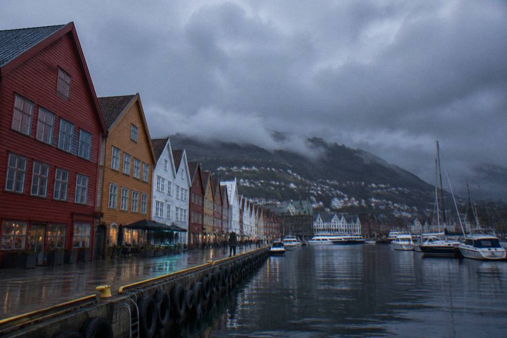 Rain clouds hanging over the colourful wooden wharf buildings and harbour of Bergen, Norway.