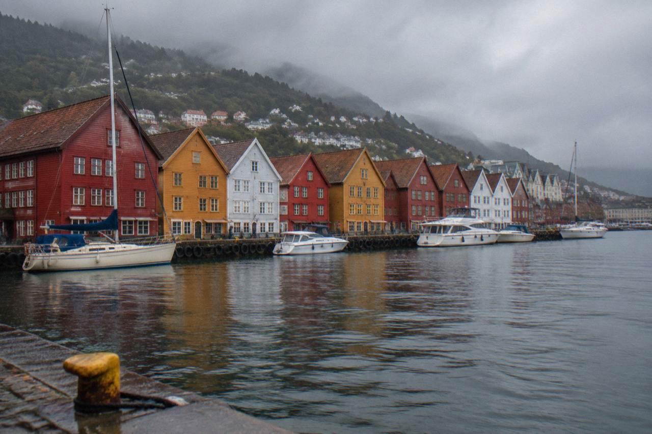 Colorful wooden Hanseatic buildings along the wharf in central Bergen with small boats on the harbor water in front of them