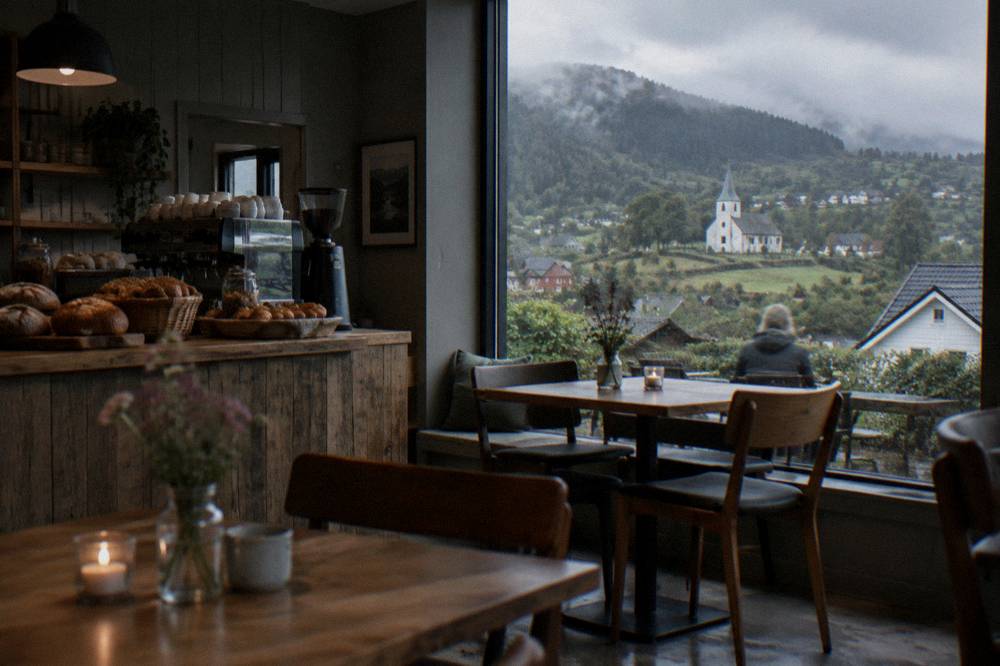 A small café interior with wooden tables, fresh bread on a counter and a coffee machine
