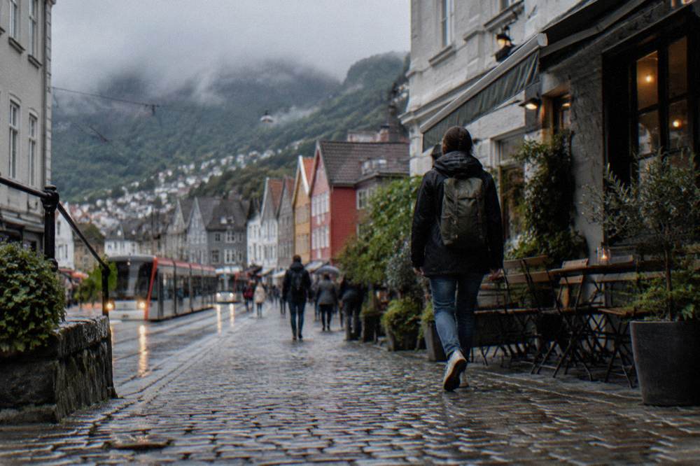 Visitor walking a cobbled lane past small cafes and shops in Bergen city centre
