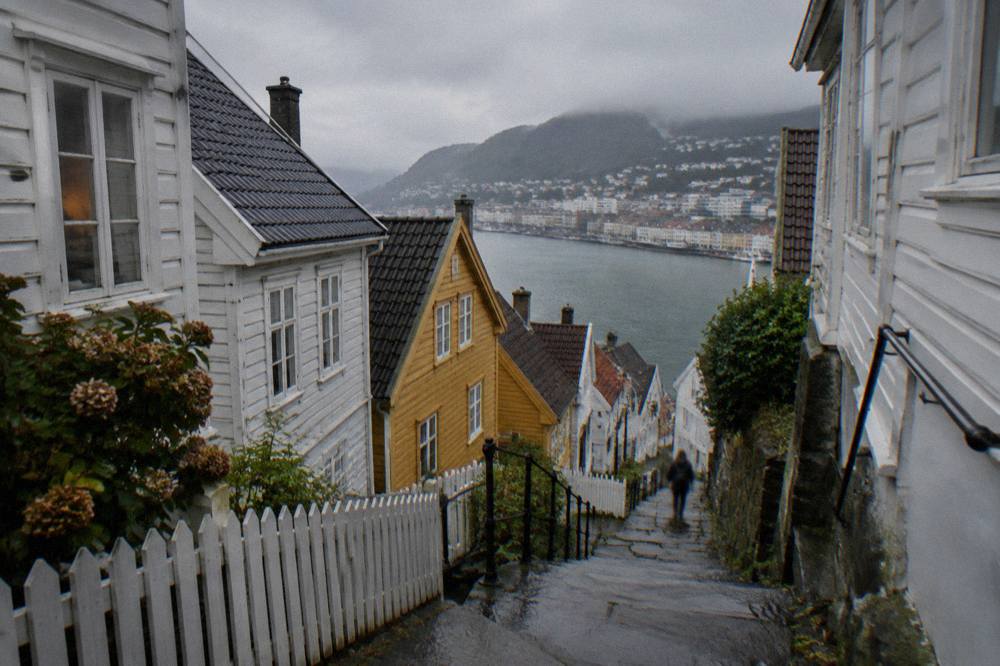 A narrow lane between whitewashed wooden houses with steep steps climbing the hillside