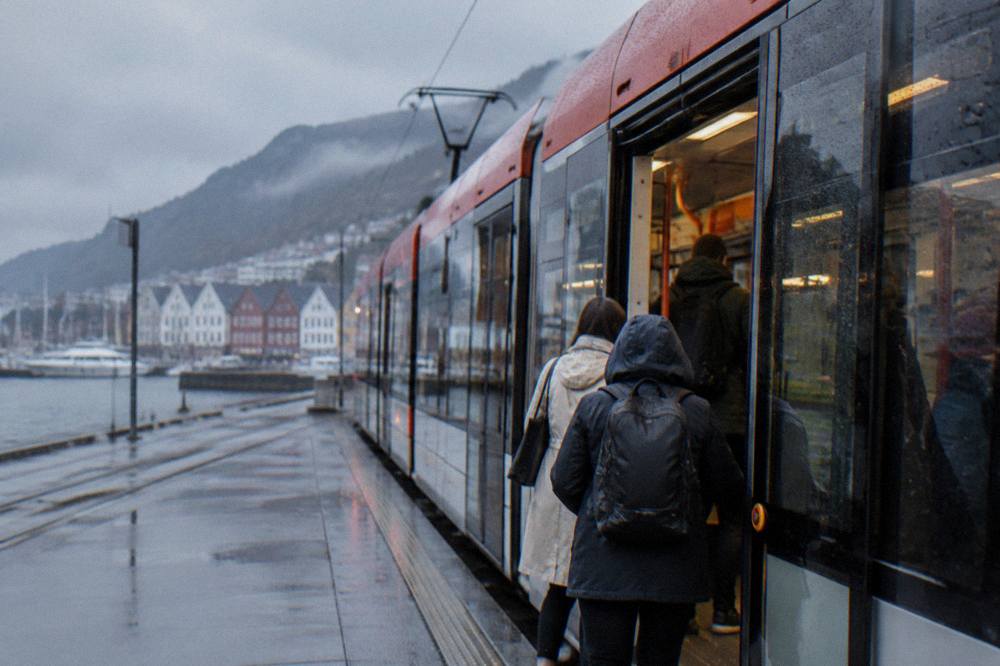 A light rail tram travelling along a street in Bergen with passengers boarding