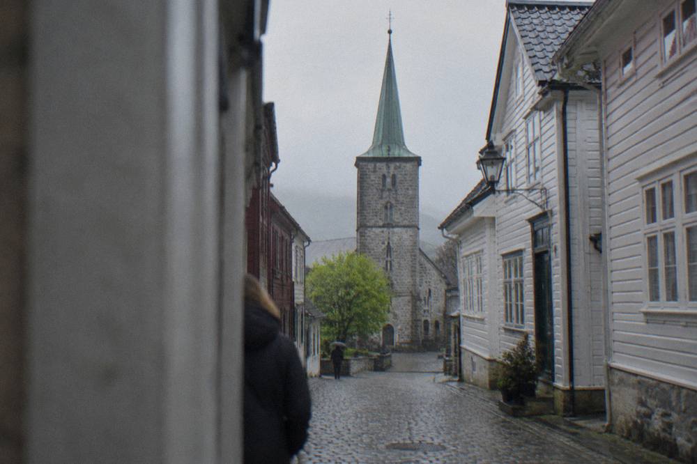A narrow cobbled street between old wooden buildings on an overcast day in a Nordic town