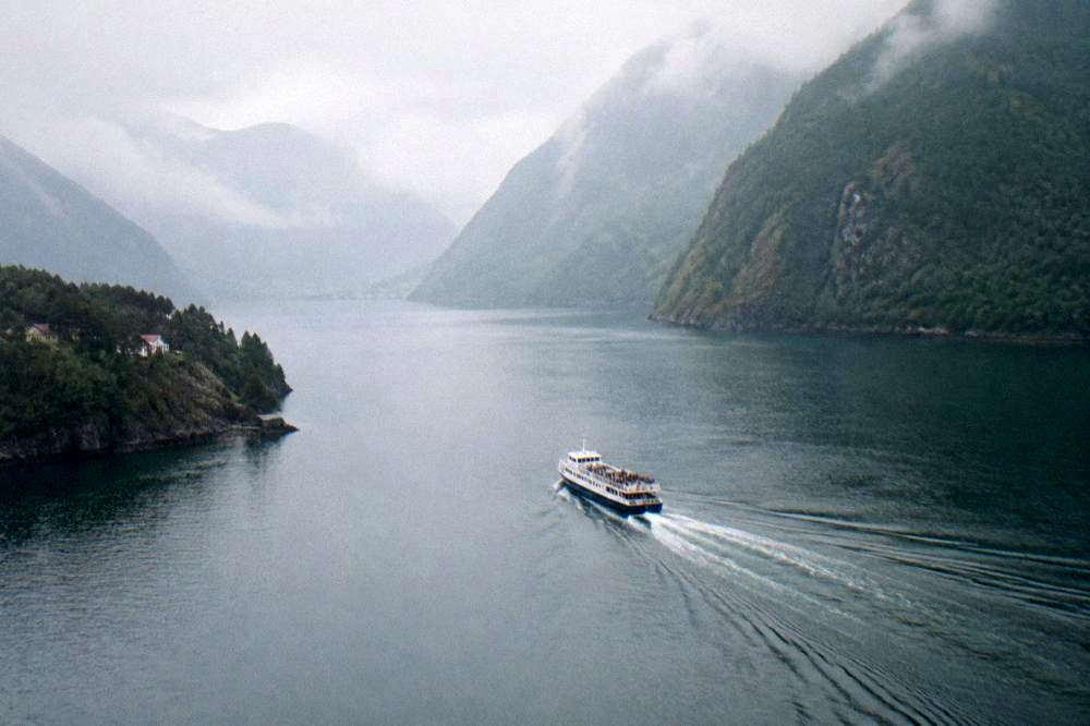 A tour boat on a calm fjord with steep forested mountains rising on both sides