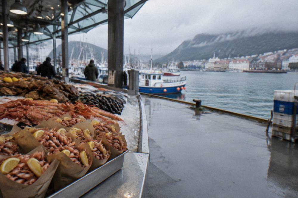 Paper cones of brown shrimp and lemon wedges on a market counter