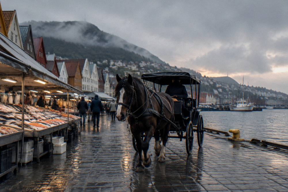 A horse-drawn carriage passing fish market stalls along the Bergen waterfront at dusk