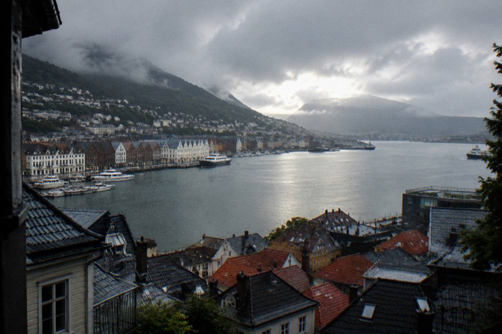 Rain falling on the roofs and harbour water of a Nordic coastal town seen from above