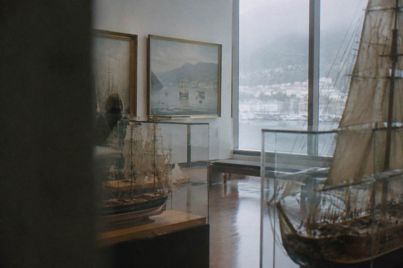 Ship models and maritime paintings displayed inside a museum hall in Bergen
