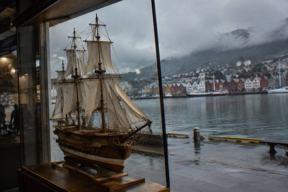 A detailed wooden model ship displayed in a glass case in Bergen