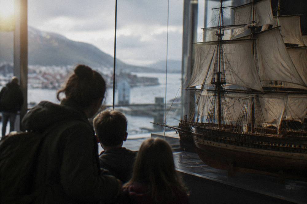 A family looking at a large ship model in a Bergen museum gallery