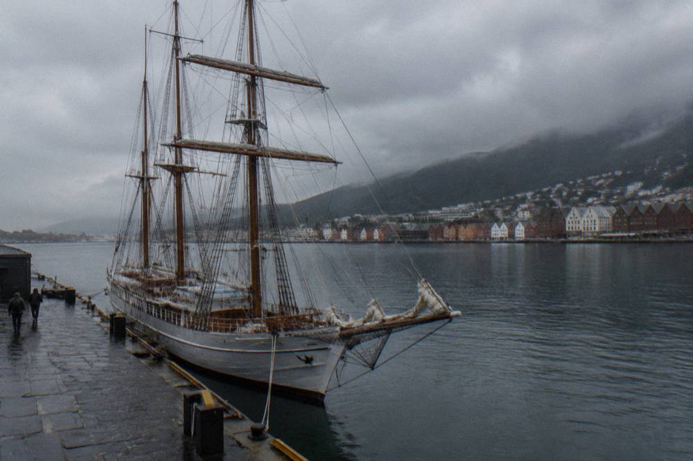 A tall ship moored at Bergen harbour seen from a stone pier