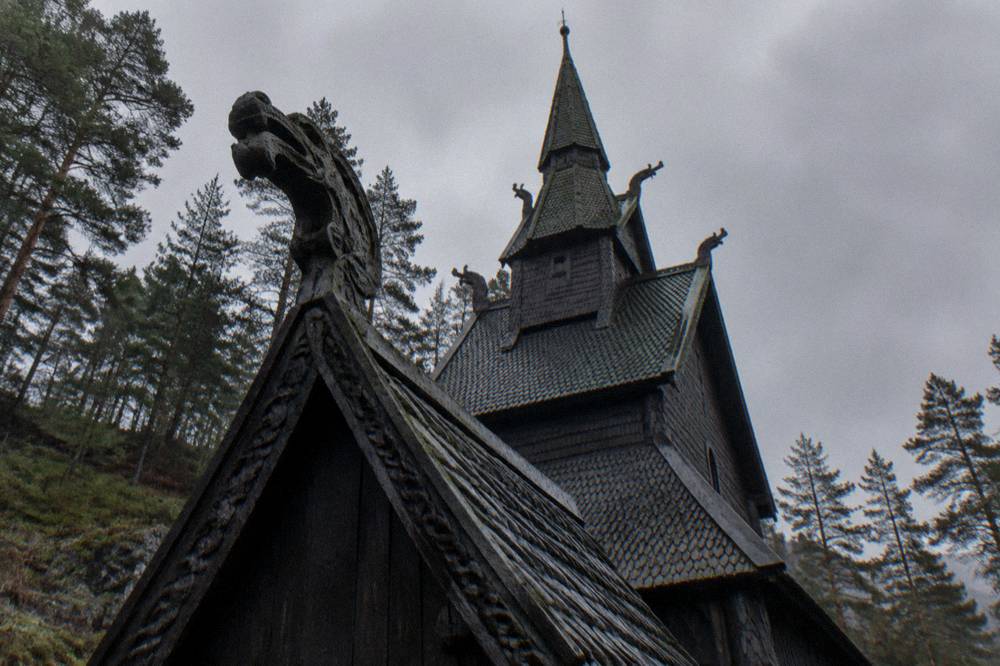A weathered carved wooden dragon-head ornament on a roof gable, darkened by rain