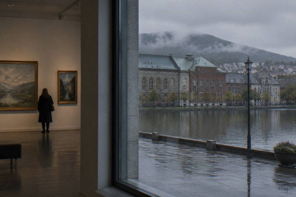 Gallery interior with paintings hung on a pale wall under soft lighting