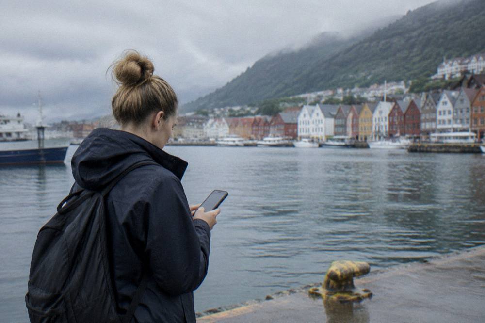 Visitor checking a phone map outside a stone museum building in Bergen