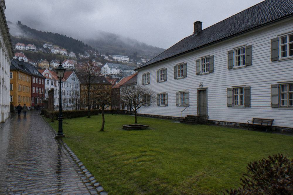 Rain-wet cobblestone street with colourful wooden houses rising up a hillside