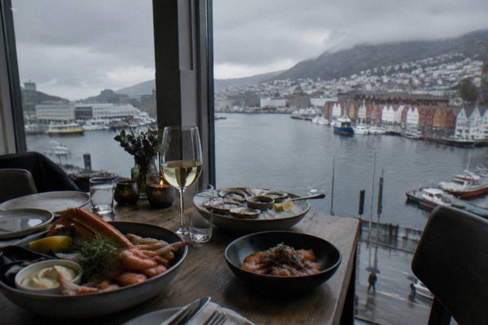 A dining table with seafood dishes and harbour views through a window