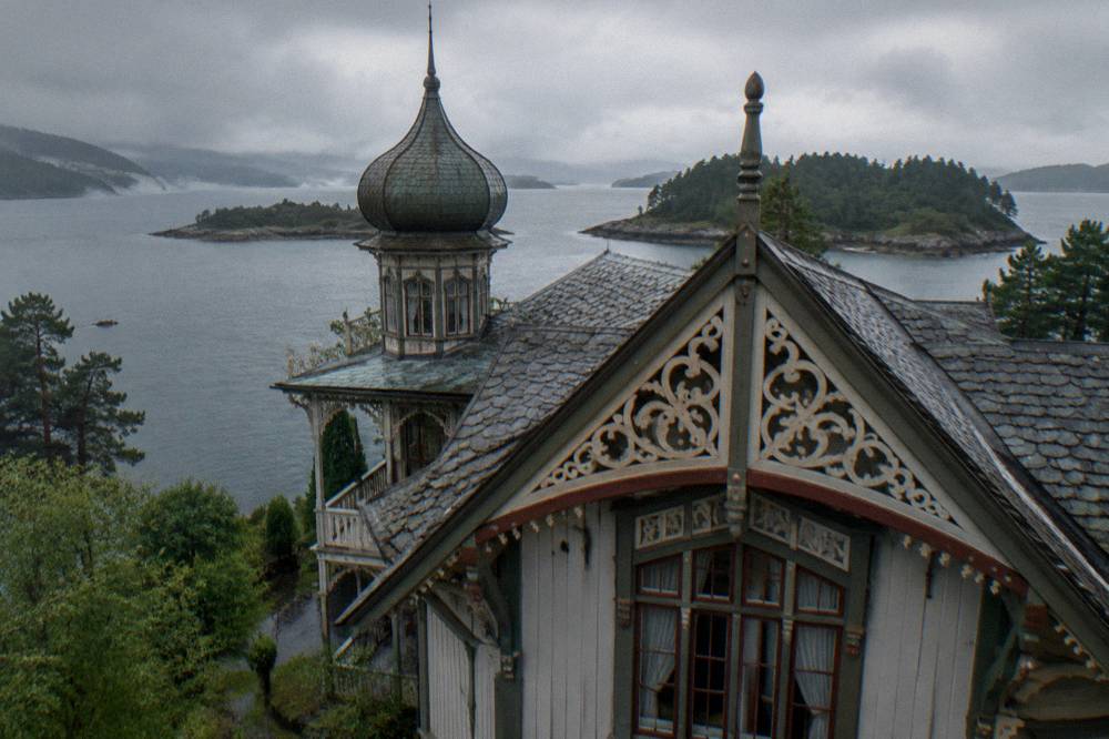 A close view of carved wooden ornamentation and painted details on the gable of a nineteenth-century Norwegian villa.