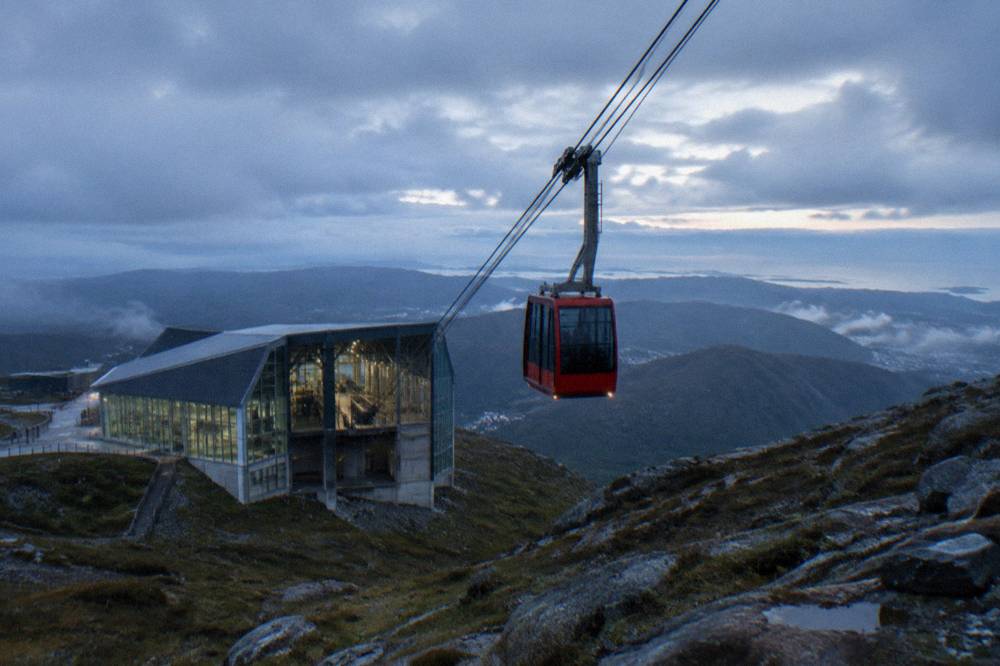 A large cable car station building with glass walls at the foot of a mountain