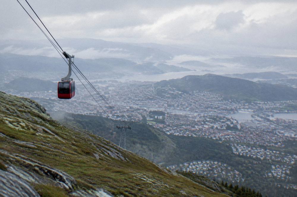A wide summit view over a dense city surrounded by water, islands and distant mountain ridges