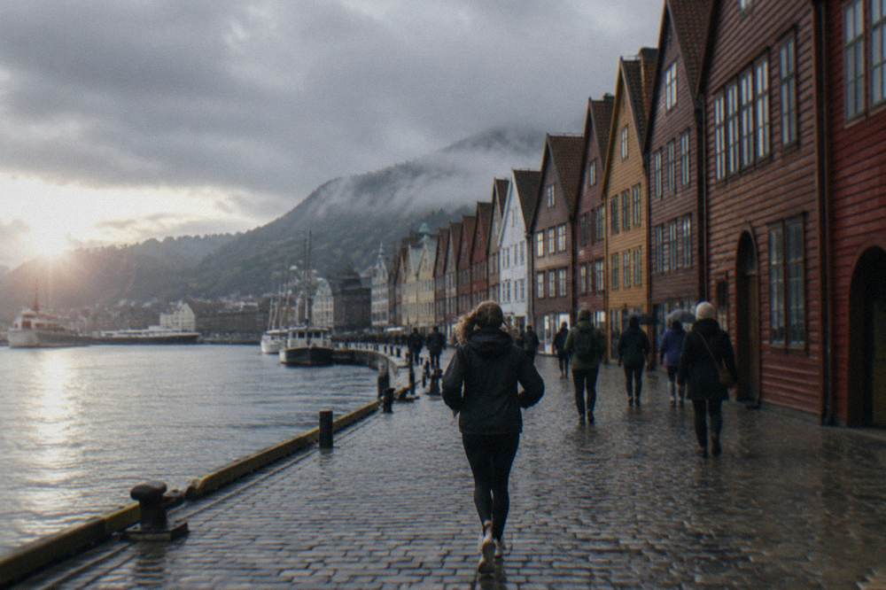 Visitors walking along the colourful wooden wharf buildings of Bryggen in Bergen