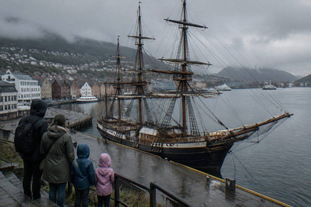A family looking at a large historic boat displayed on the Bergen harbourfront