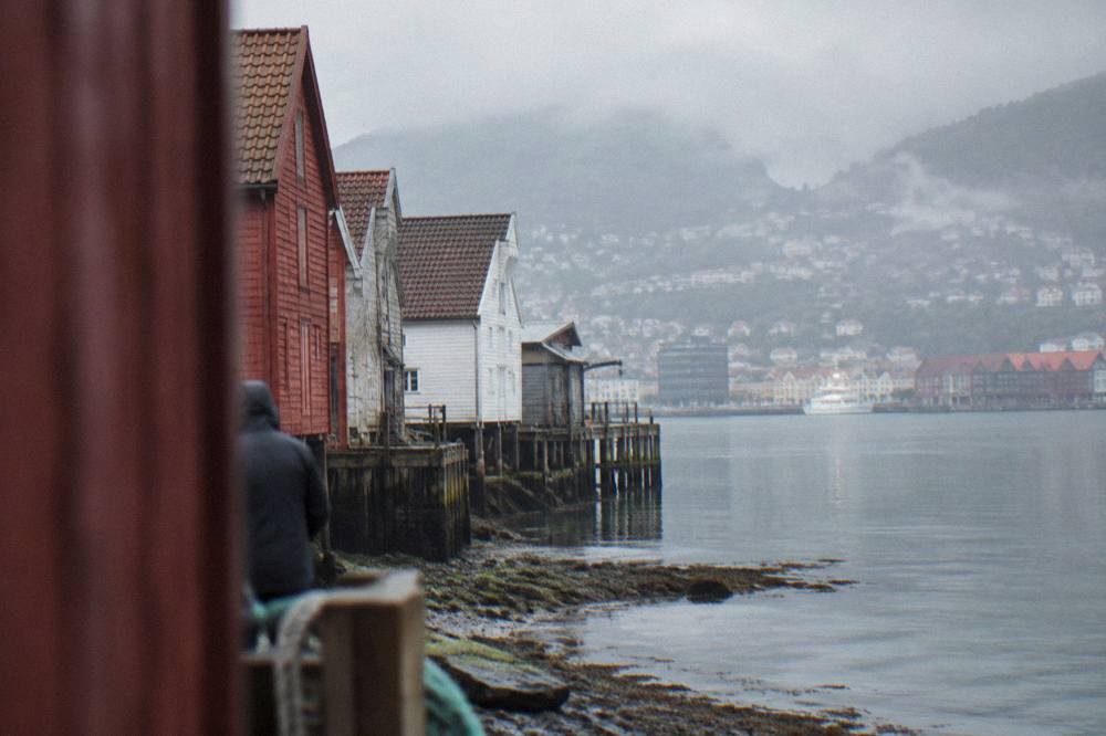 Wooden boat sheds and wharf pilings along the Bergen waterfront at low tide