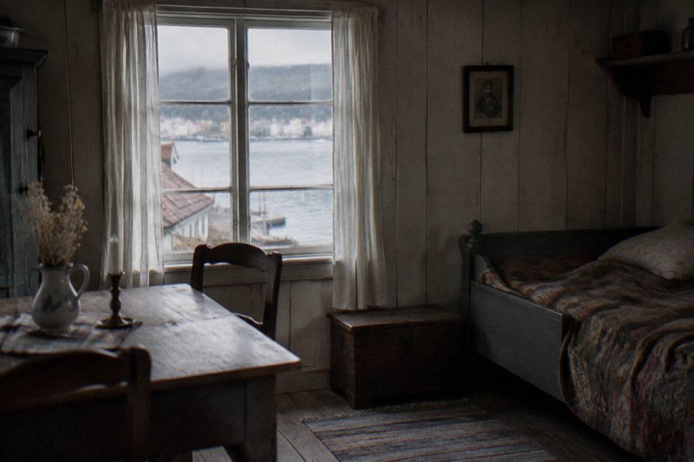 A period room inside a wooden house with old furniture and a small window