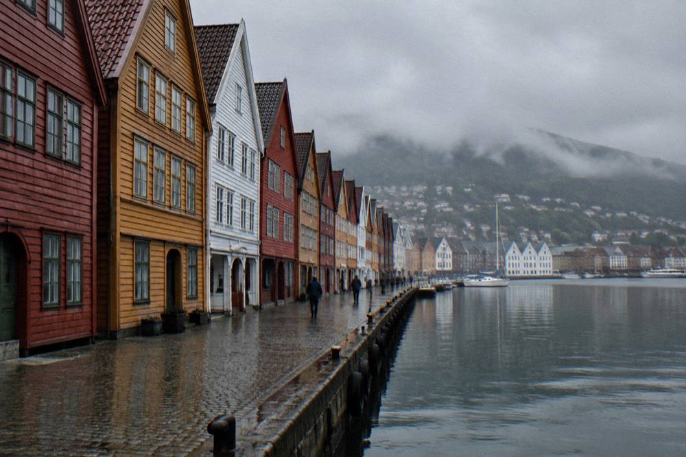 The painted wooden Hanseatic wharf at Bryggen reflected in harbour water