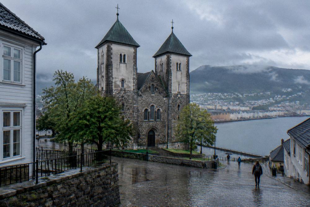 Church tower seen across wet cobblestones with reflections from a light rain shower
