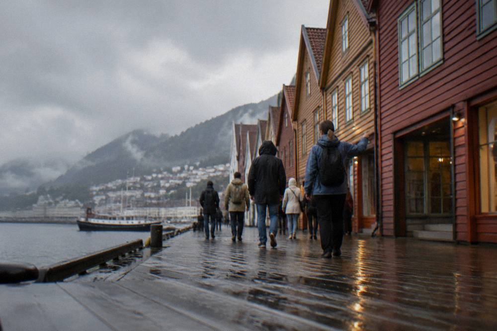 Small group of visitors following a guide along the wooden buildings at the Bergen wharf
