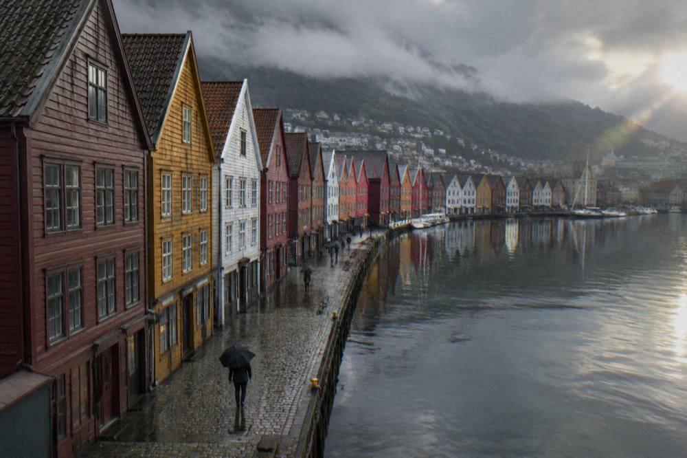 Colourful wooden buildings along the Bryggen wharf reflected in harbour water at Bergen