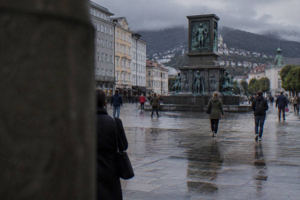 People walking across the wide open paving of Bergen's main square on a mild overcast day