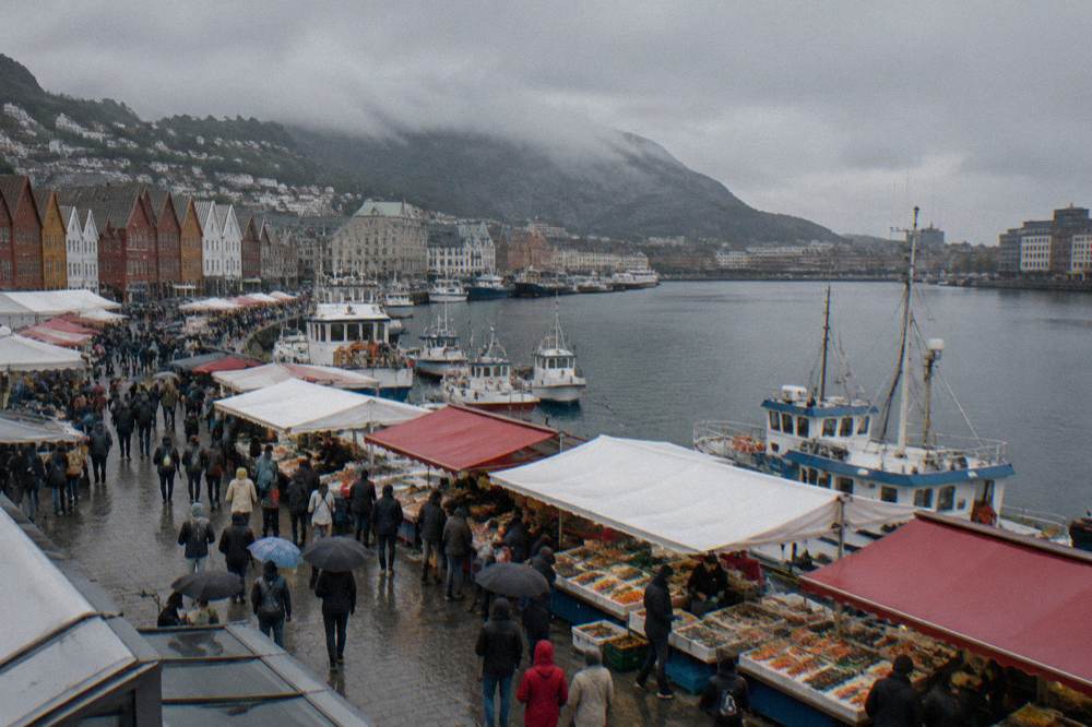 A harbour-side food market with stalls of fresh seafood and crowds of visitors in Bergen