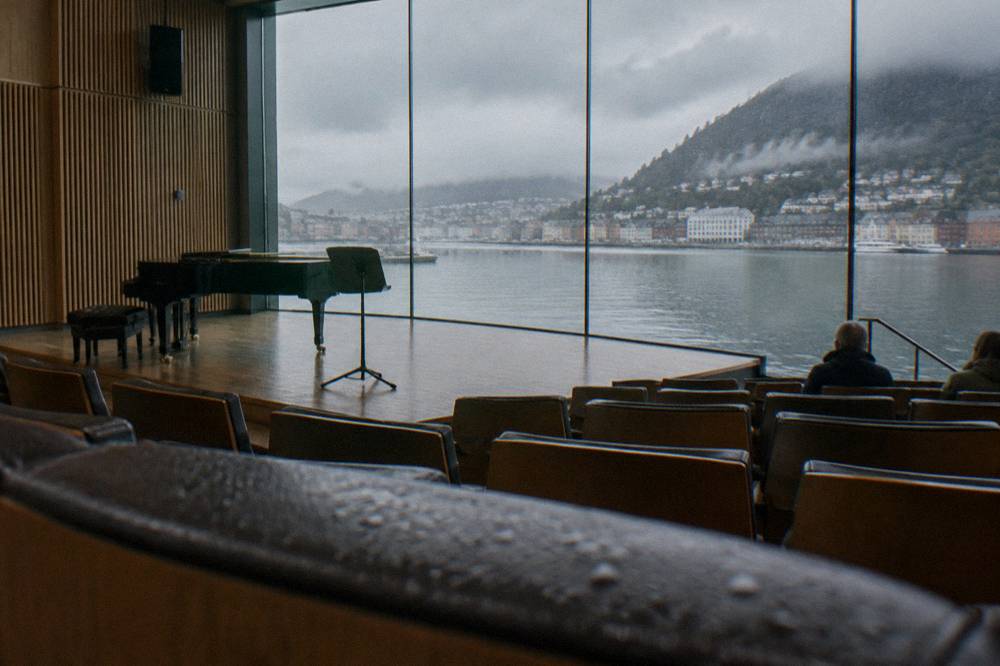 A small concert hall with rows of seats and a large window overlooking a lake