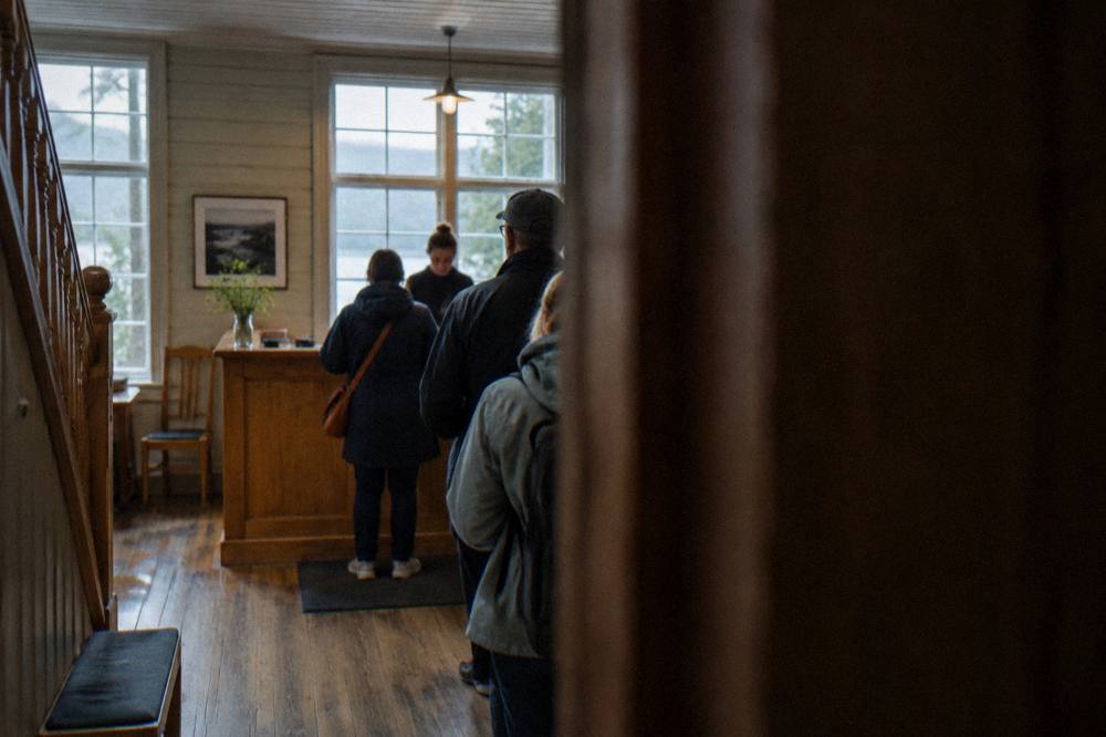 A ticket desk in a wooden museum lobby with a small queue of visitors